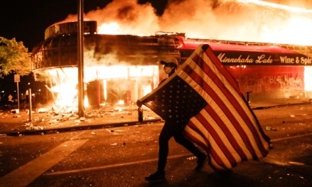 A man is carrying America Flag on fire
